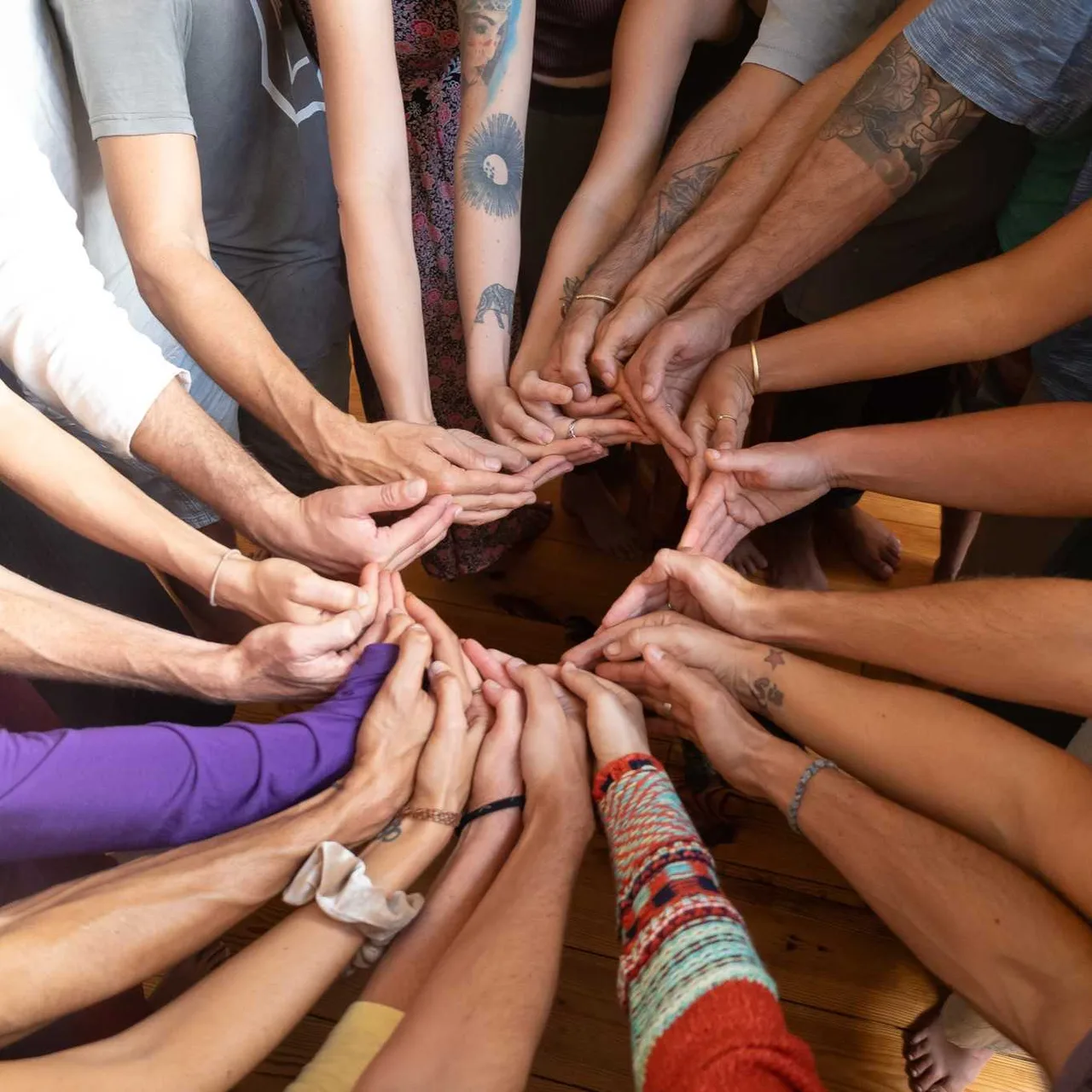 A circle of NVC training participants stacking hands together